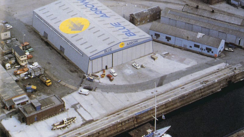 Aerial view of Pendennis Shipyard around 1988, featuring the Blue Arrow building and surrounding industrial docks.