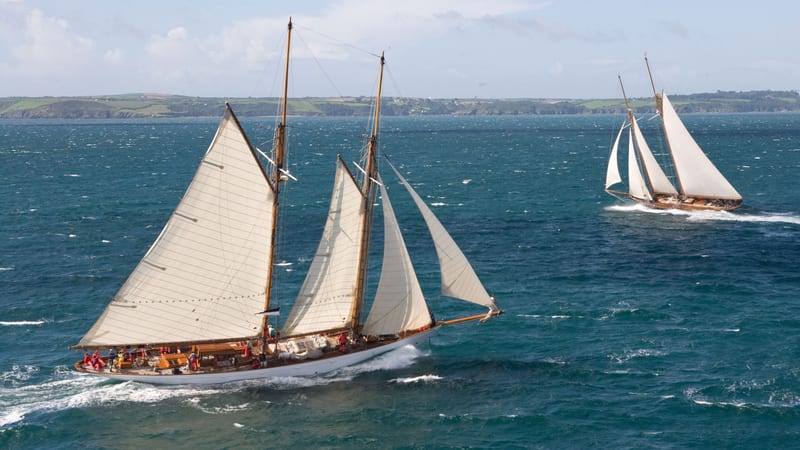 Classic sailing yachts racing off the Cornish coast during the Pendennis Cup regatta.