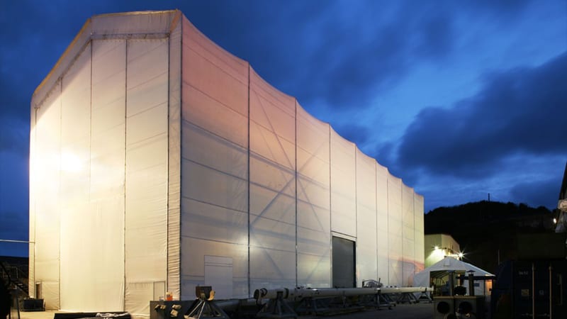 Large illuminated temporary structure at Pendennis Shipyard, known as the White House, lit up at night.