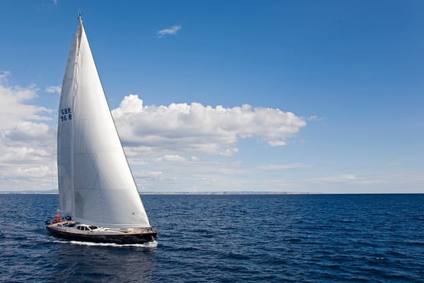 Sailing yacht Margaret Ann glides through open water under full sail on a clear day with distant land on the horizon.
