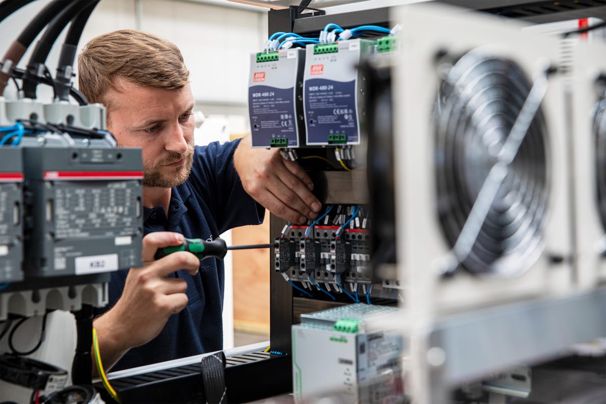 Technician adjusting control panel wiring on a superyacht electrical system.