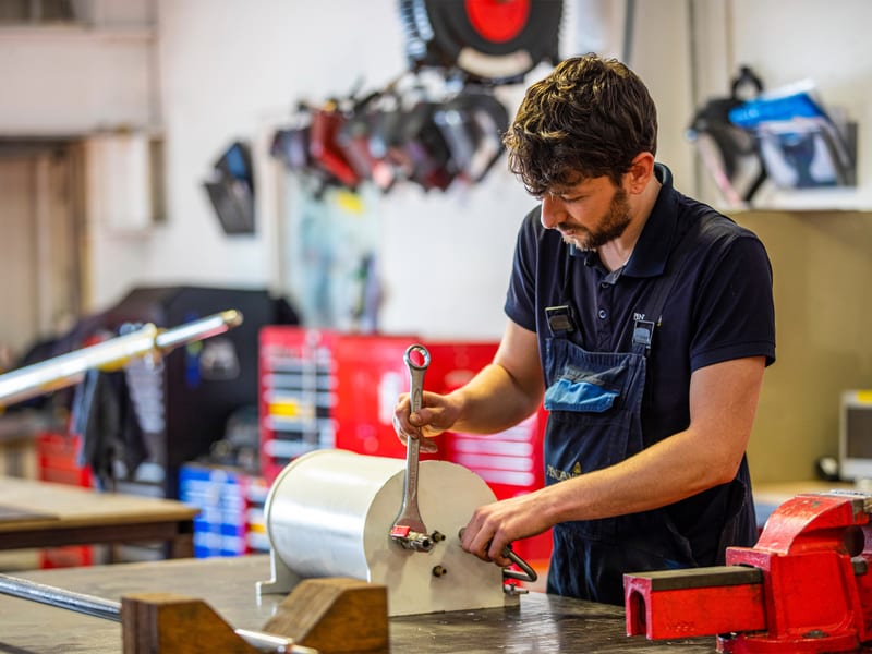 Engineer assembling mechanical components in the workshop with hand tools.