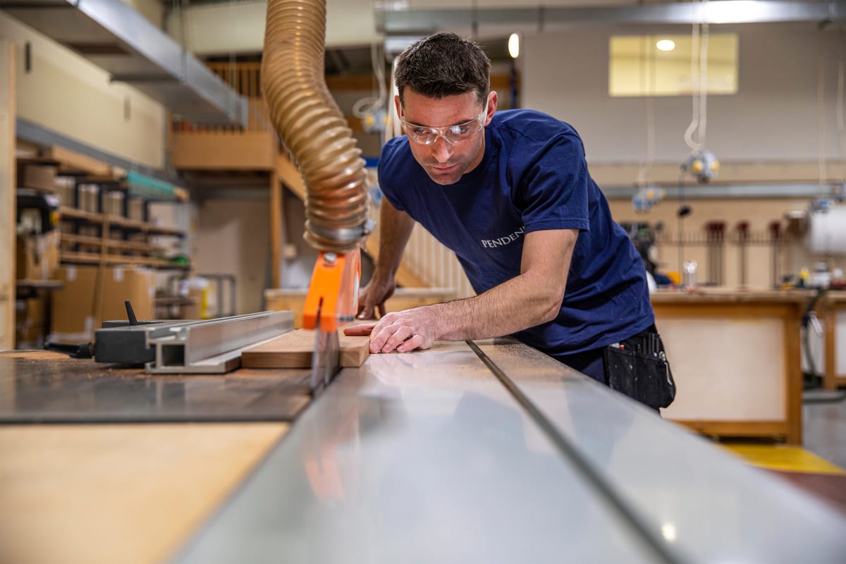 Shipwright using a table saw to cut timber inside the Pendennis joinery workshop.
