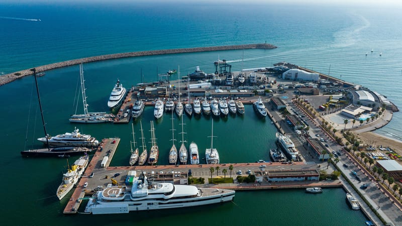 Aerial view of Pendennis Vilanova marina and shipyard on a bright day, with yachts berthed along multiple piers.
