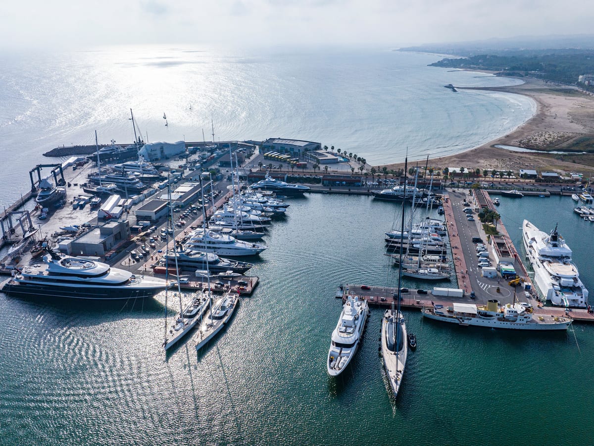 Aerial view of Pendennis Vilanova marina and shipyard on a bright day, with yachts berthed along multiple piers.