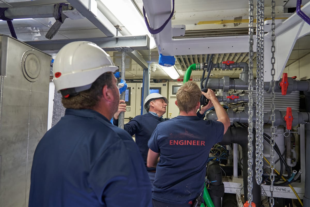 Three men visually inspecting the engine room
