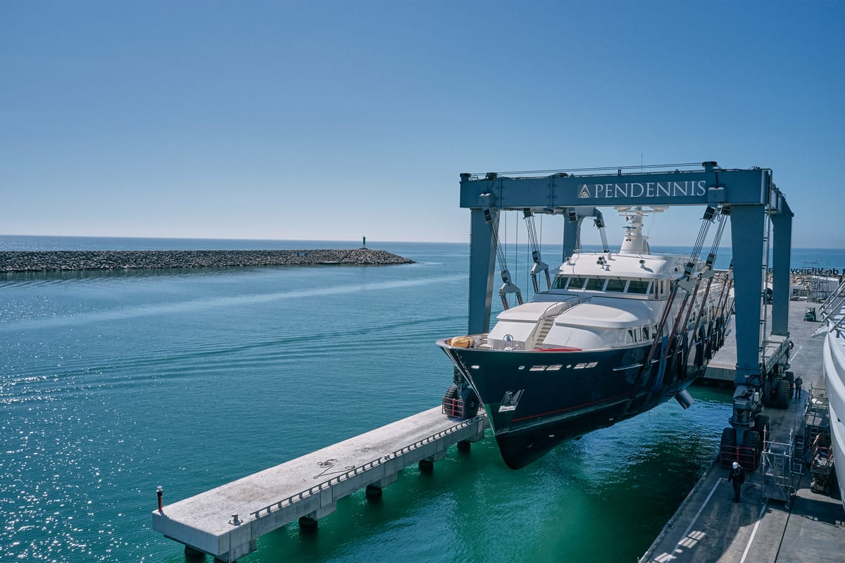 A motor yacht suspended over the water in a travel hoist