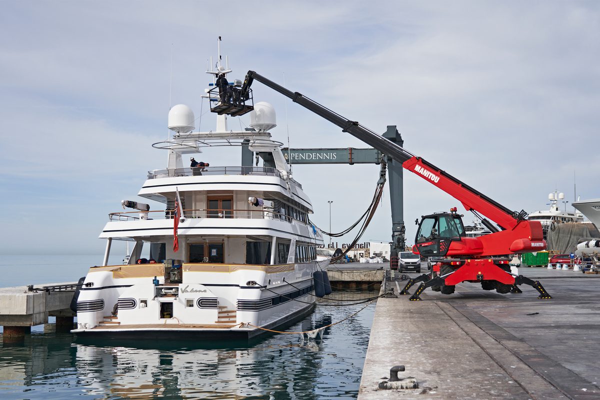 A crane positioned next to a motor yacht in a haul out bay