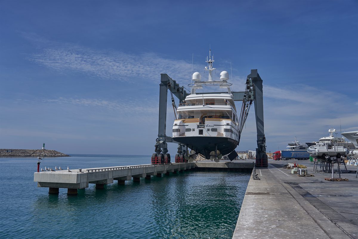 A motor yacht is suspended over water in a travel hoist