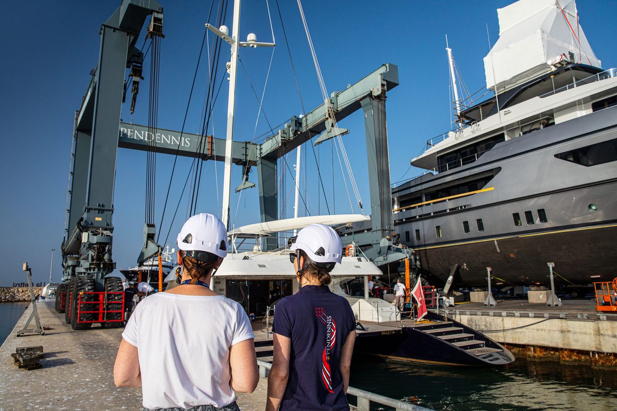 Two Pendennis team members observe a superyacht being lifted from the water at the Vilanova Technical Service Centre.