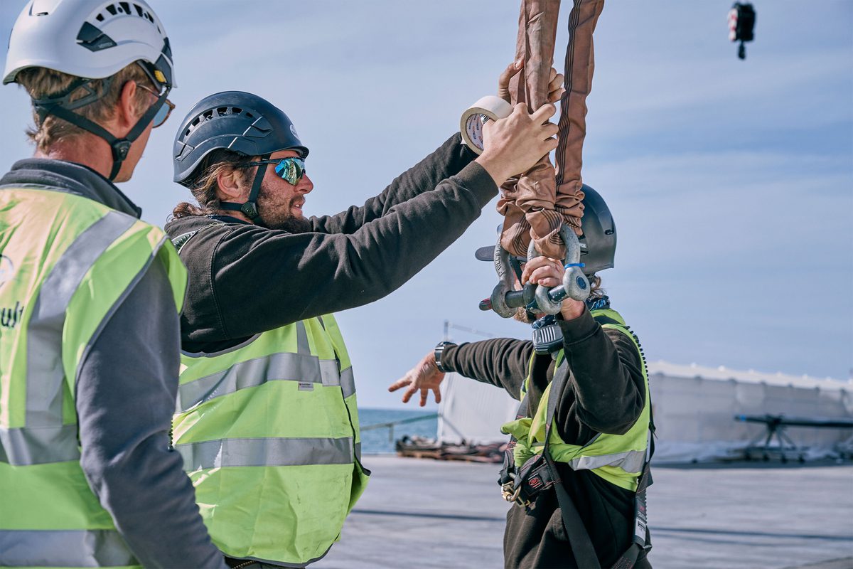 Rigging team securing lifting slings with tape during yacht mast stepping at Pendennis Vilanova.